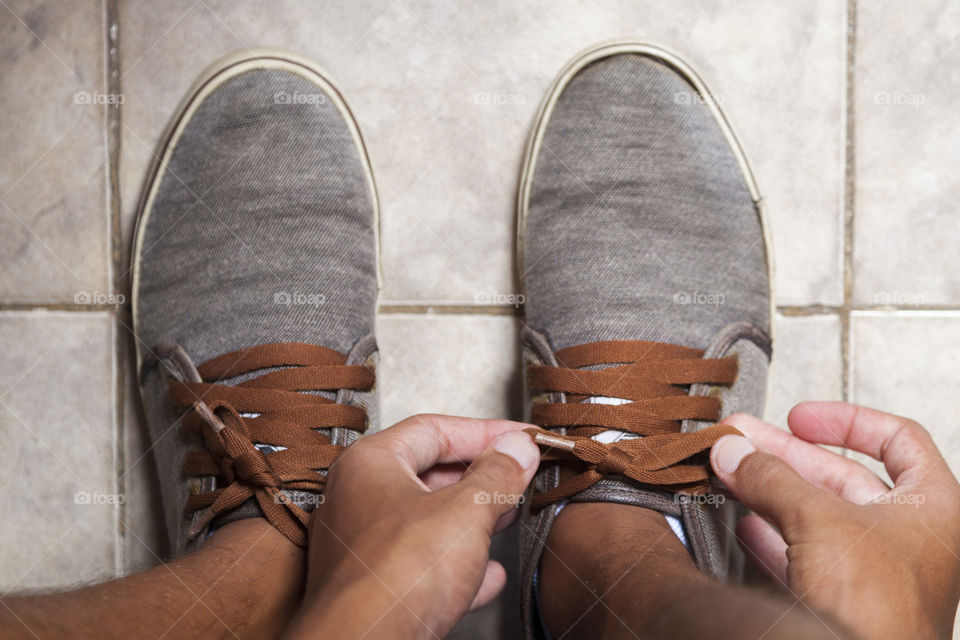 Young sportsman tying up tennis before going out to do running exercise in the morning