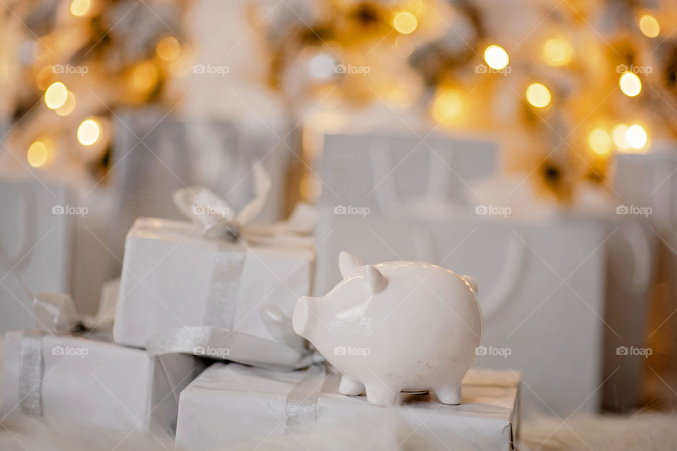 piggy bank with 100 dollars banknote in festive New Year atmosphere of scenery.  Magical bokeh with Christmas tree and bright lights.