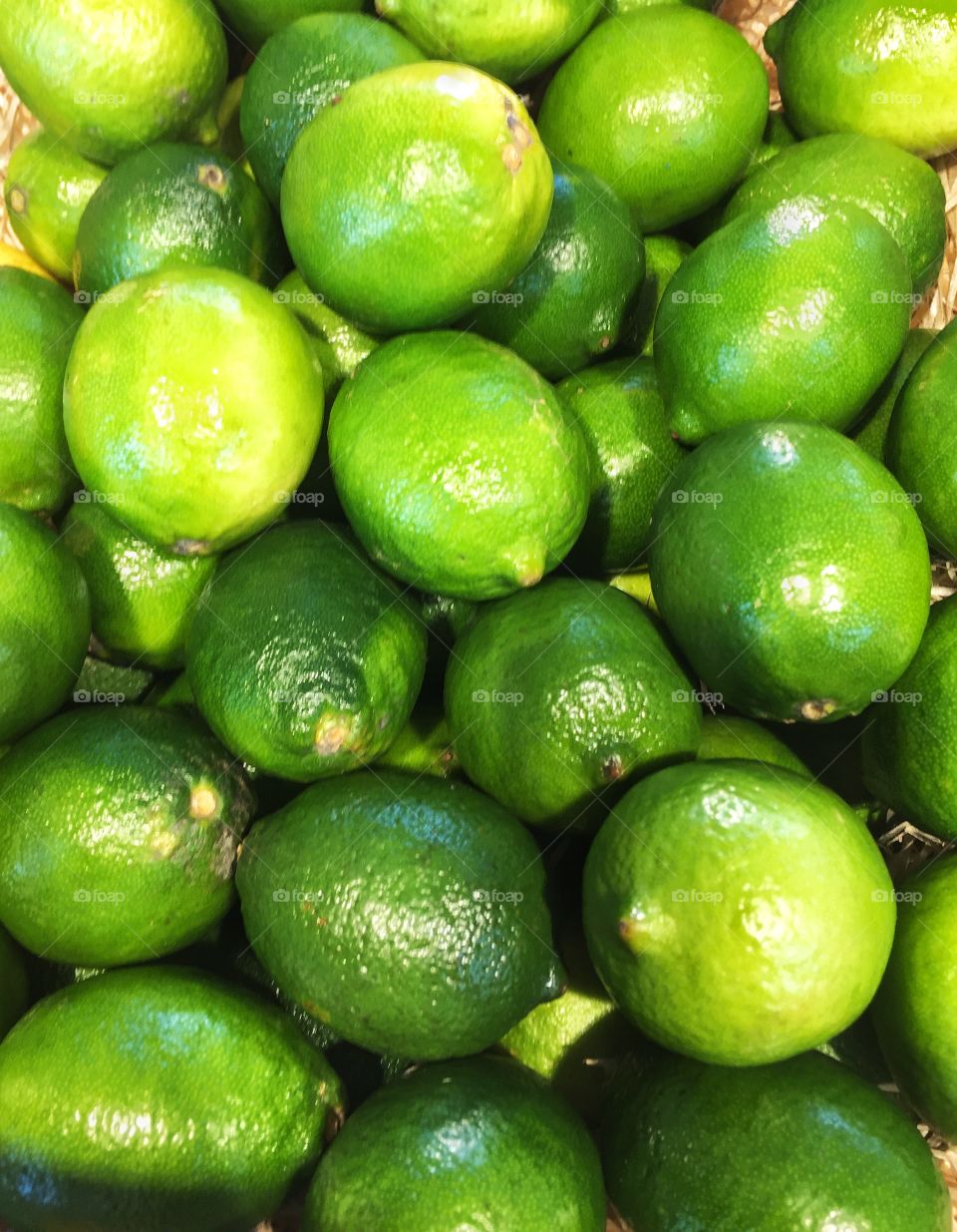 A full frame background of fresh, organic green limes on a market stall