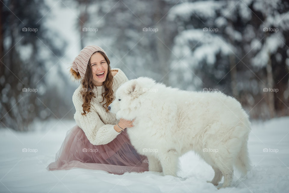 Young woman with Samoyed dog in winter park 