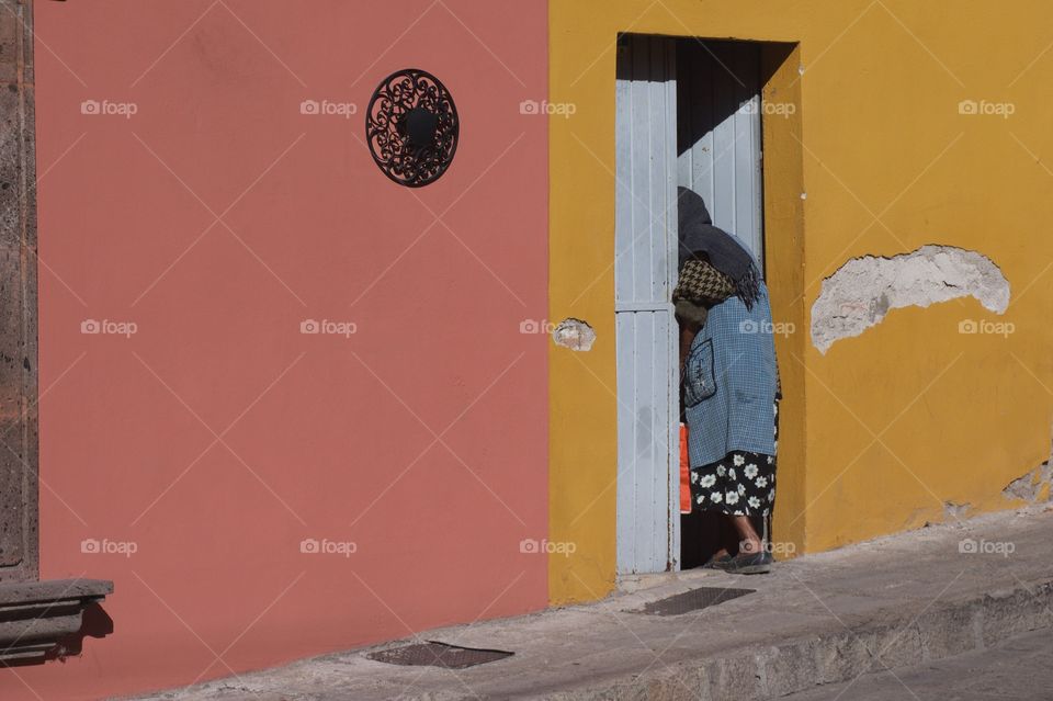 Old woman enters door in house