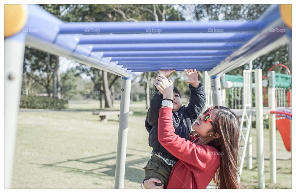 Mother helping her son in playground 