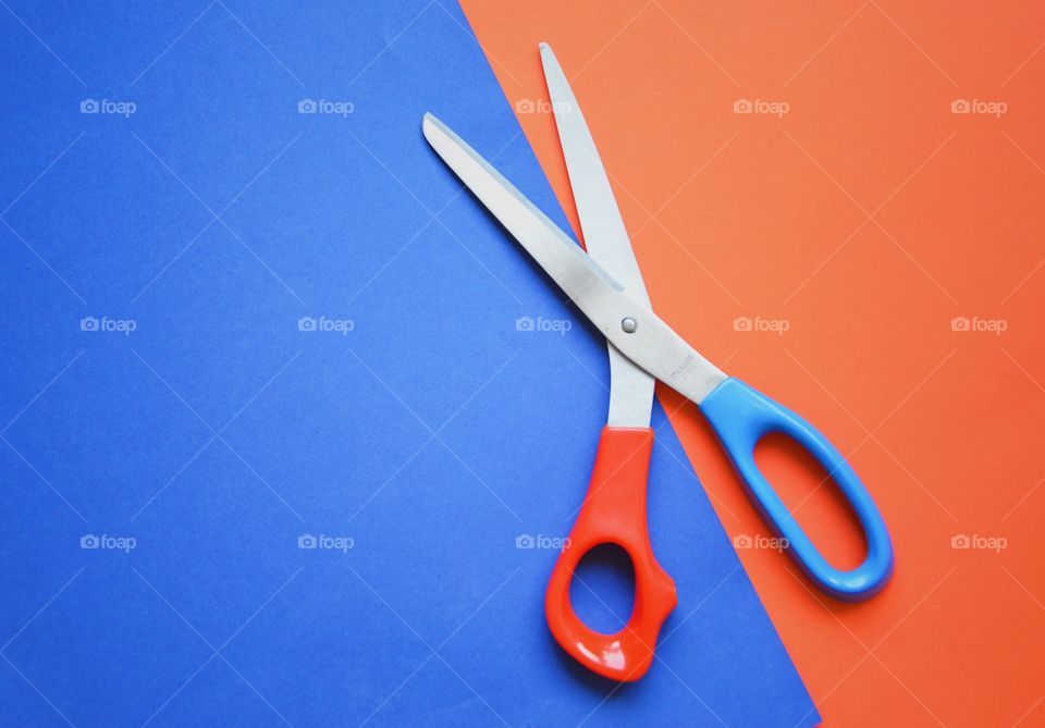 Flat lay of a scissor on red and blue background 