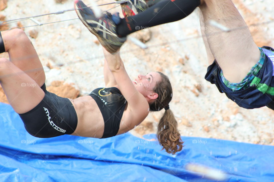 Woman competing in the Battlefrog Atlanta obstacle course race. Hanging over and traversing pit.