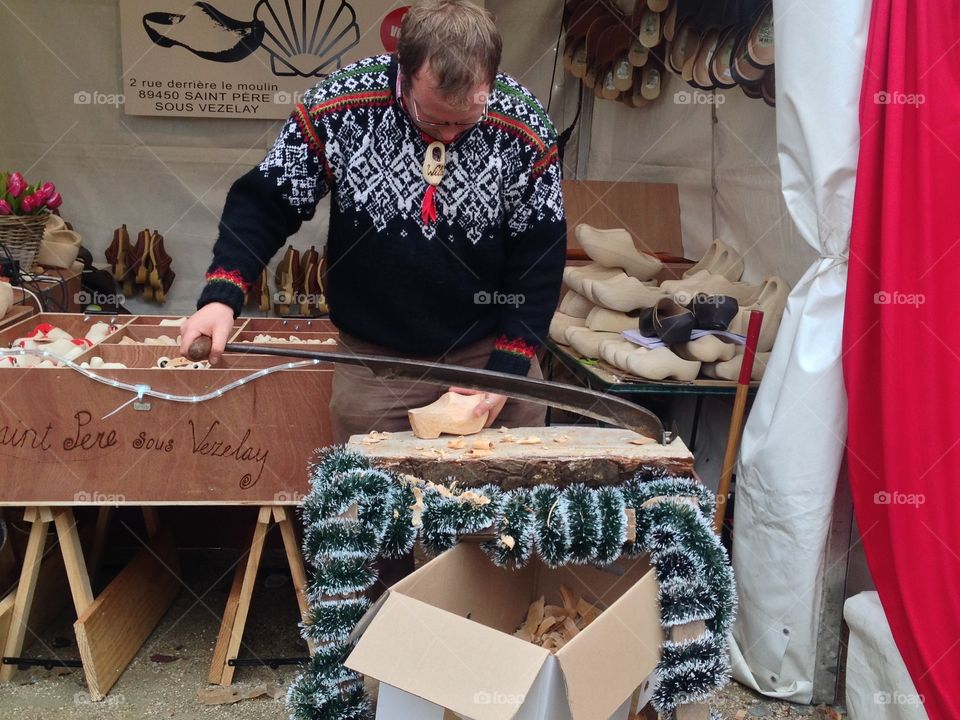 A craftsman at a Christmas Market in Paris just outside Notre Dame shapes wooden clogs. 