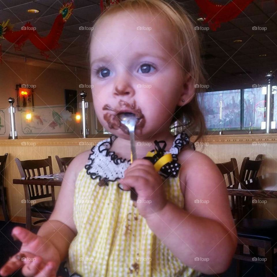 Little girl eating chocolate in restaurant
