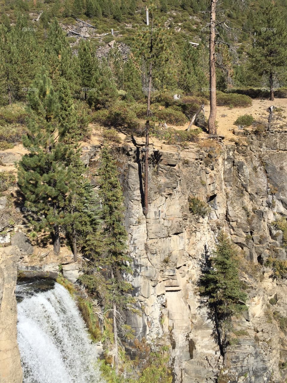 Tumalo Falls in Central Oregon falling down the side of a cliff on a fall day full of sunshine. 