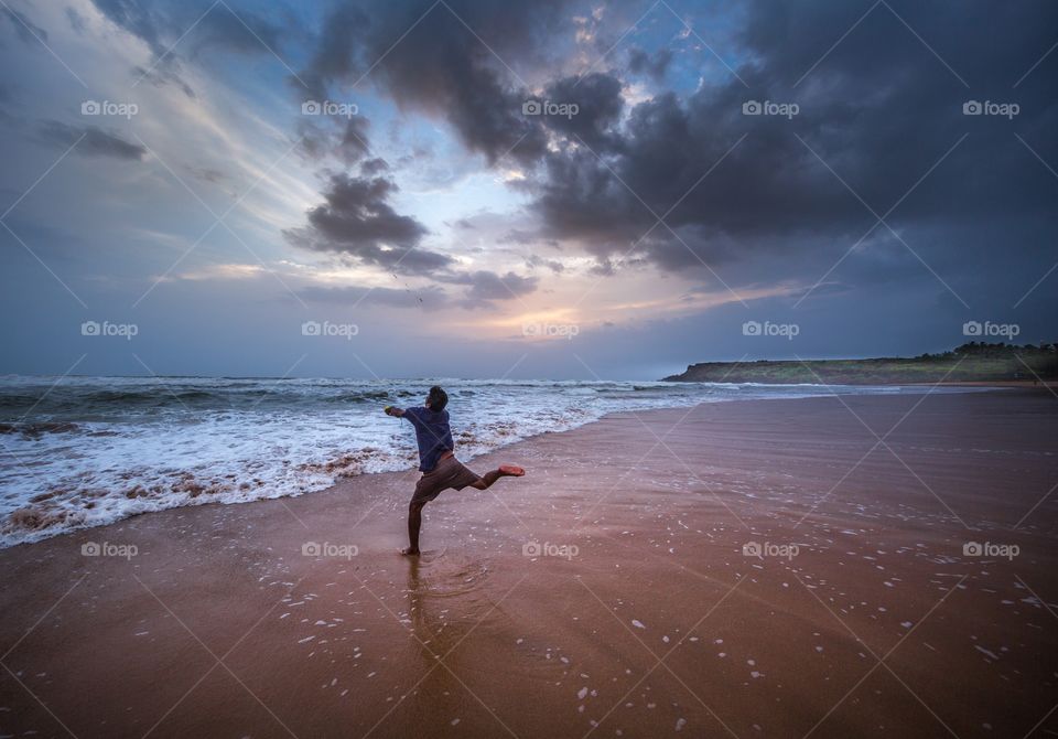 fisherman throwing fishing net into the sea during sunset