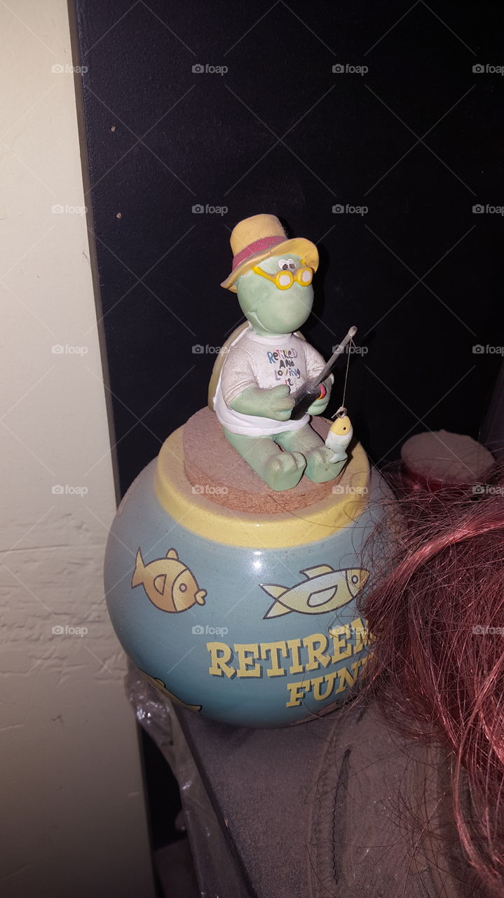 A turtle that is fishing sitting on top of this cookie jar. Funny for people who are retiring.