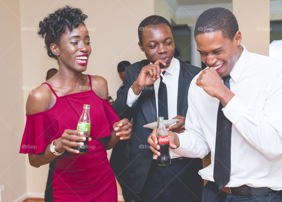 African friends holding cold drink bottle and laughing