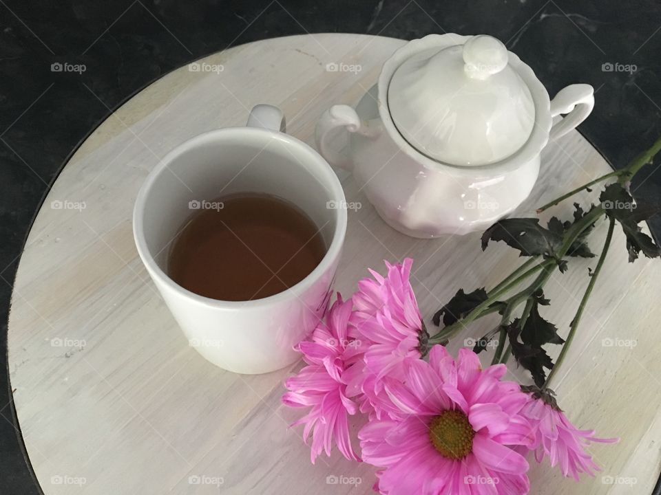 Pink flower with tea cup and teapot on table