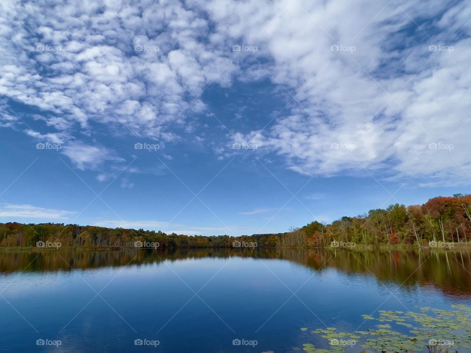 Colorful autumn foliage casts its reflection on the calm waters of Upstate New York.