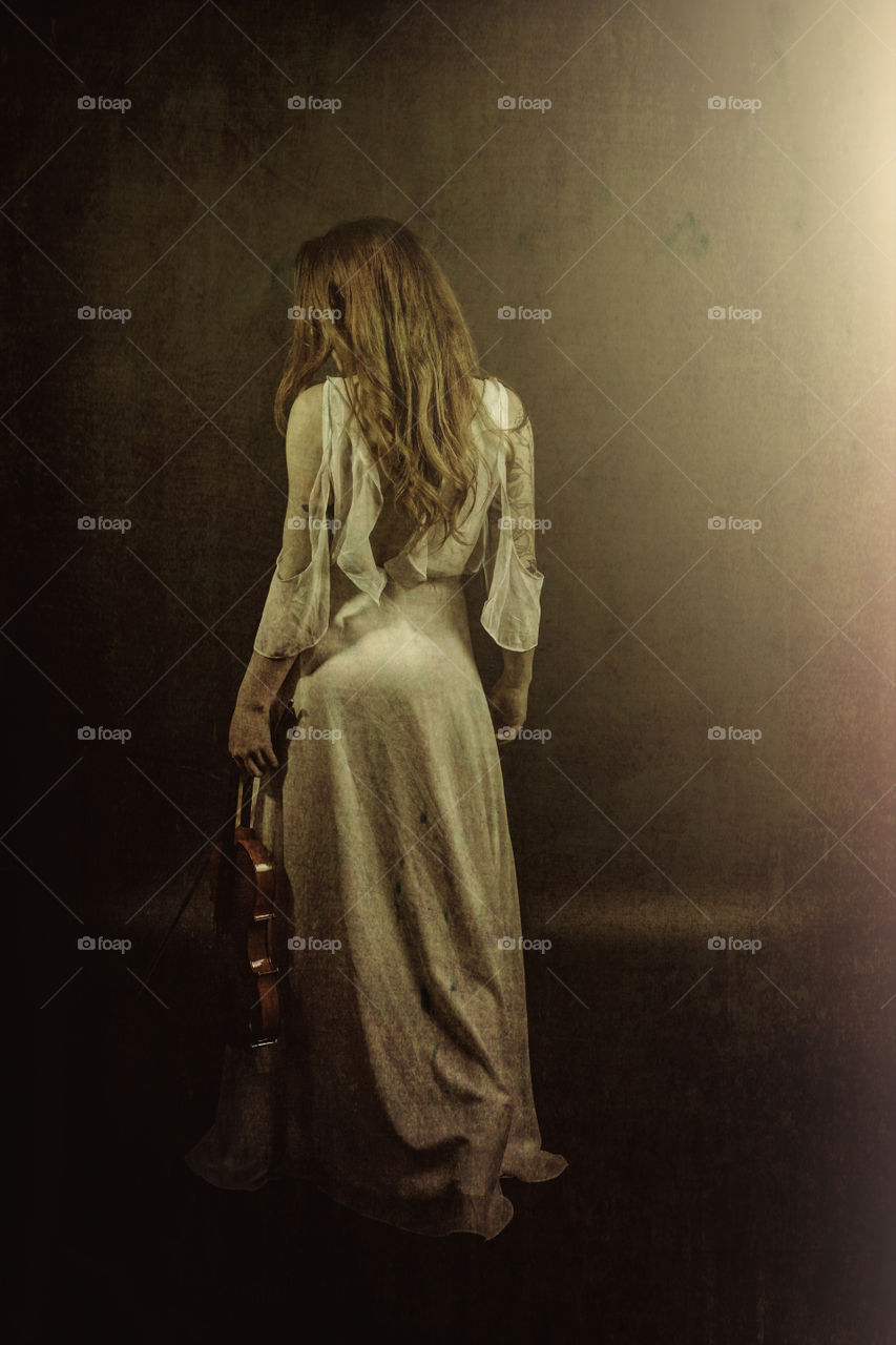 Girl with violin walking away. Lighting from right of image