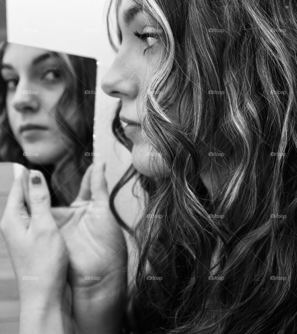 Black and white image of girl looking into mirror 