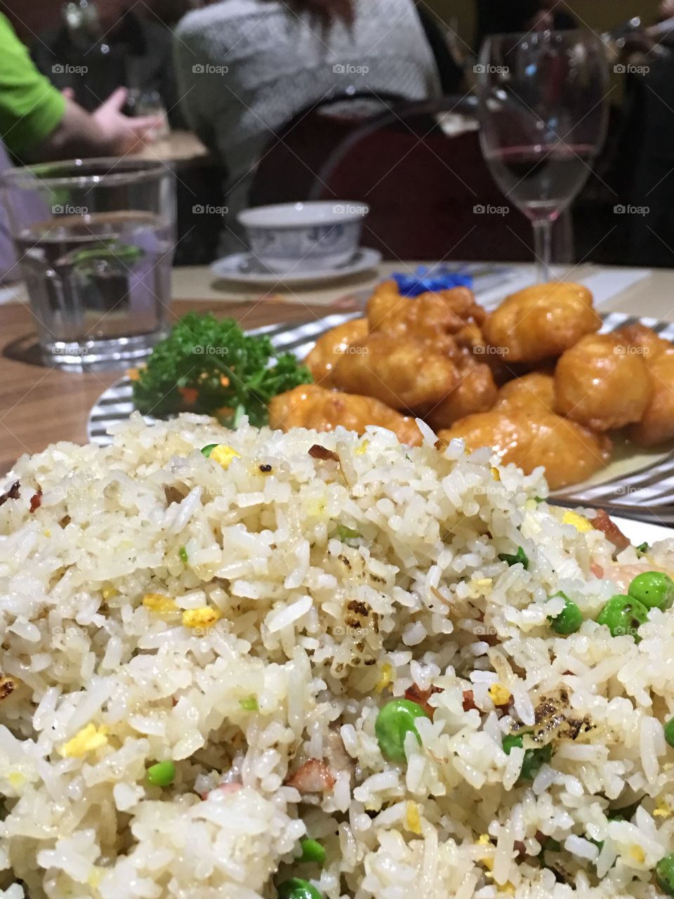 Two Chinese food dishes on plates, fried rice foreground and lemon chicken background closeup Asian food 