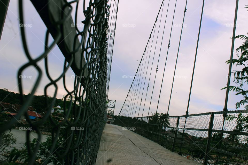 There are several paths in the form of slings that function to hang iron bars as a support for the suspension bridge floor. This is done so that the suspension bridge is strong from all the objects that pass through it.