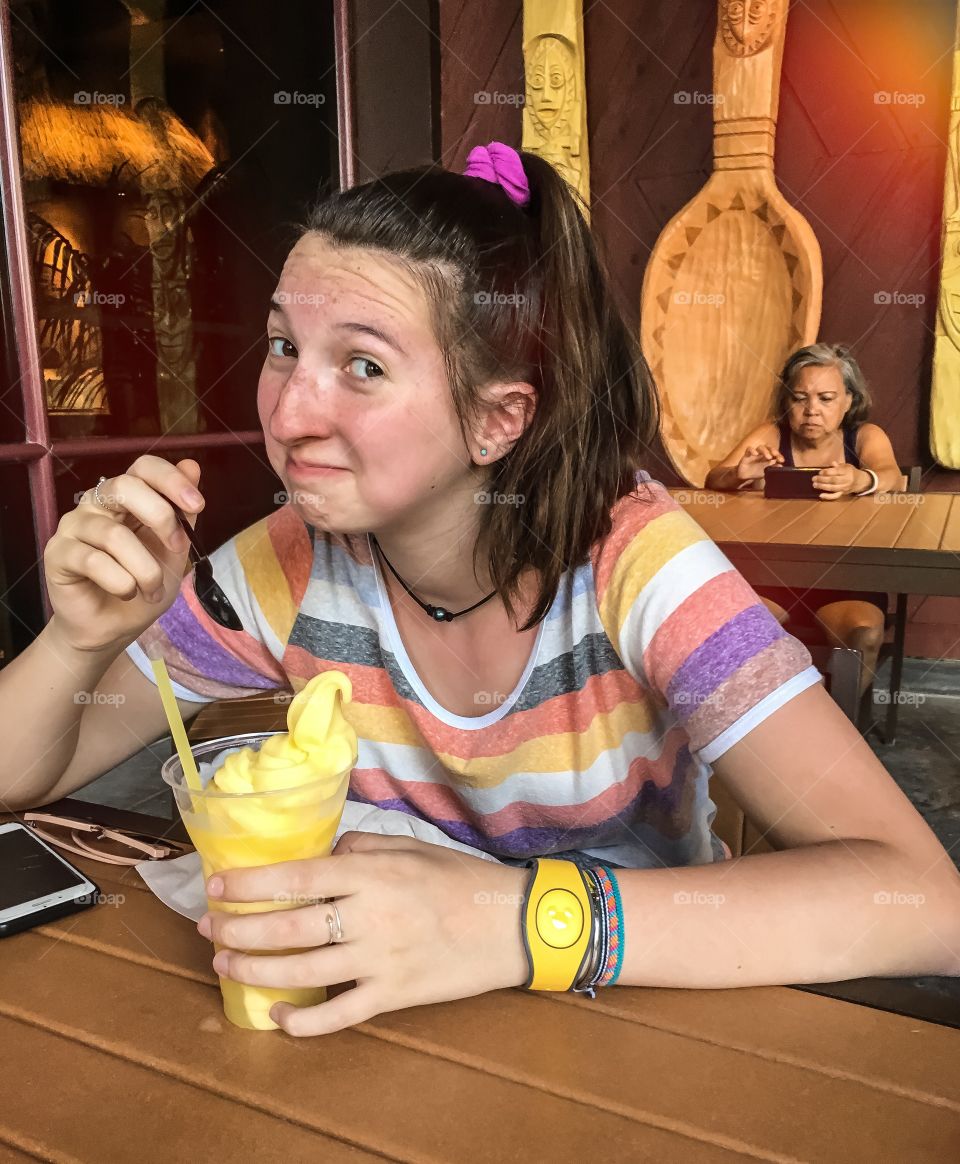 Dole whip is delicious.  Teenage girl enjoying a cold treat on a warm Florida, winter day. 