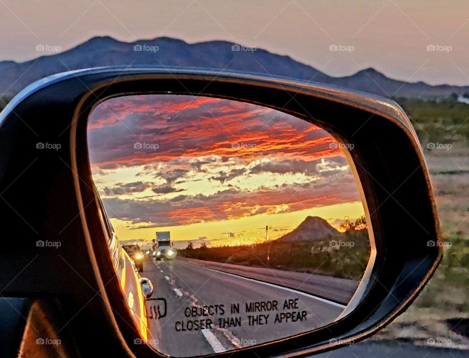 A beautiful sunset appears in the side mirror somewhere on the interstate between Los Angeles and Phoenix