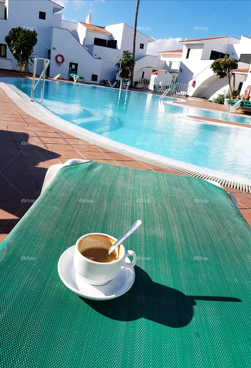 The calm is coming in. Vacation at the pool with a good cup of coffe.