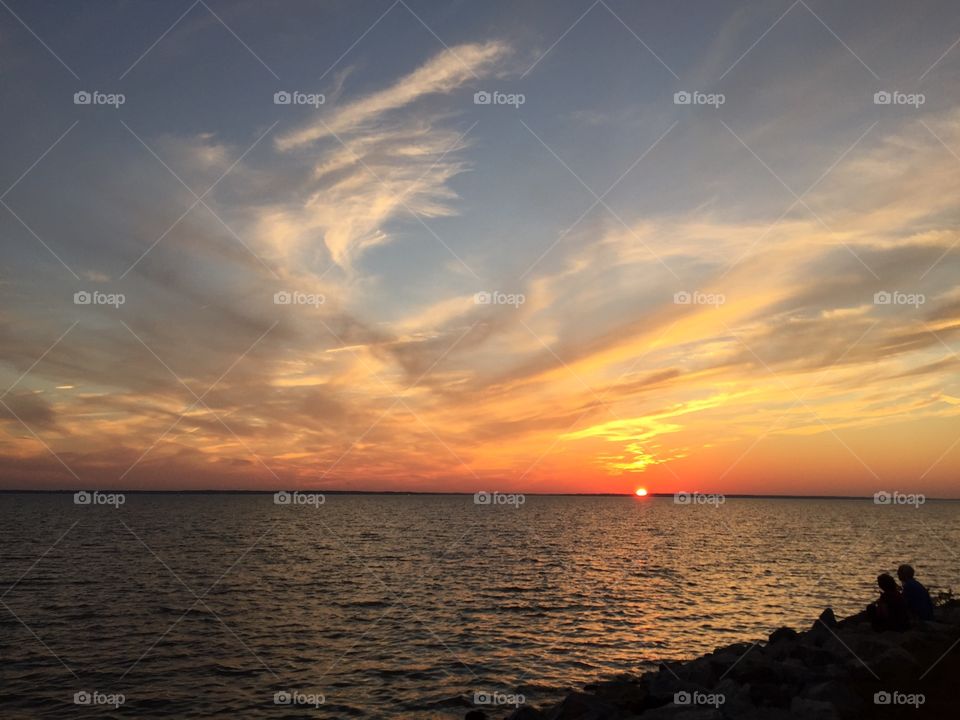 Couple watching a beautiful and stunning Sunset at the Chesapeake bay bridge In Chesapeake, Virginia. 