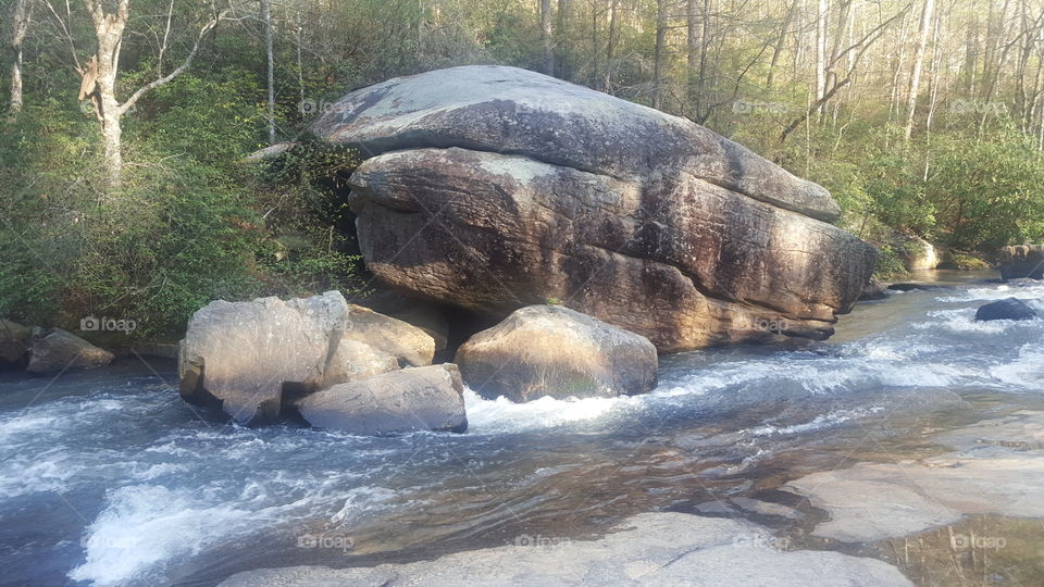 creek flowing by big boulder