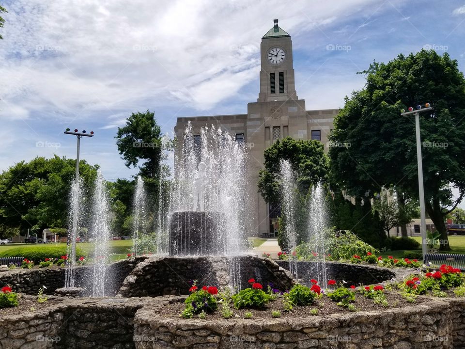 Round fountain with statue and garden in front of an old stone building in Sandusky, Ohio