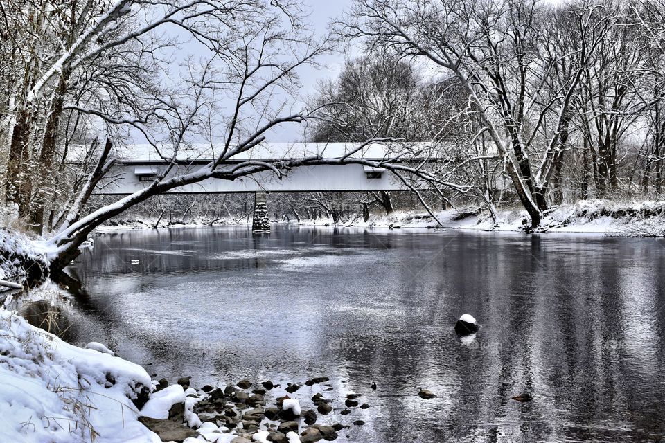 Covered bridge on a snowy cold Indiana day along the white river with snow on the bridge 