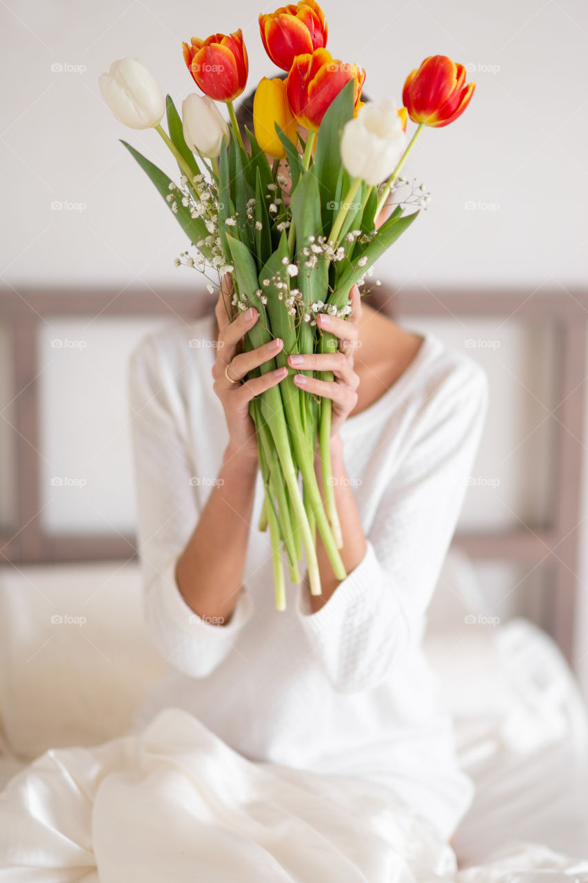 Happy girl smiling and holding a spring bouquet of tulips