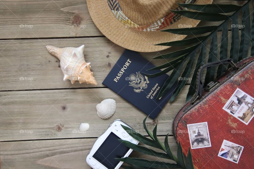 Travel items flat lay with hat camera suitcase and sea shells