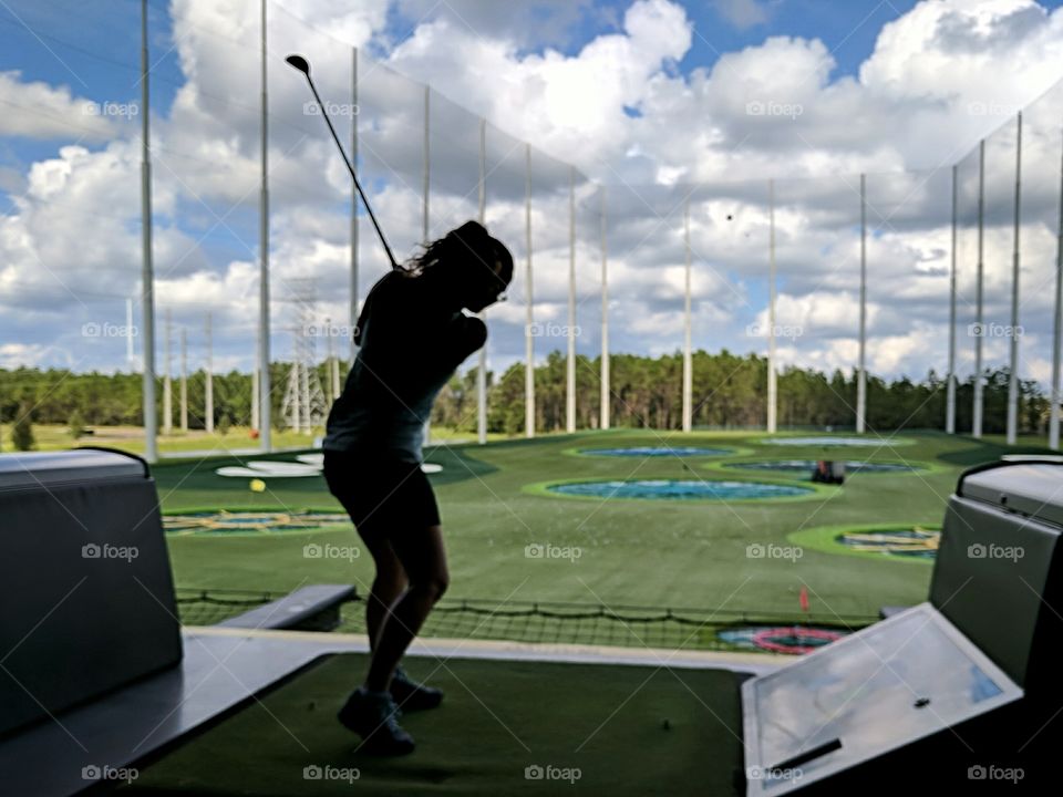 woman playing golf at a driving range with arcade style targets