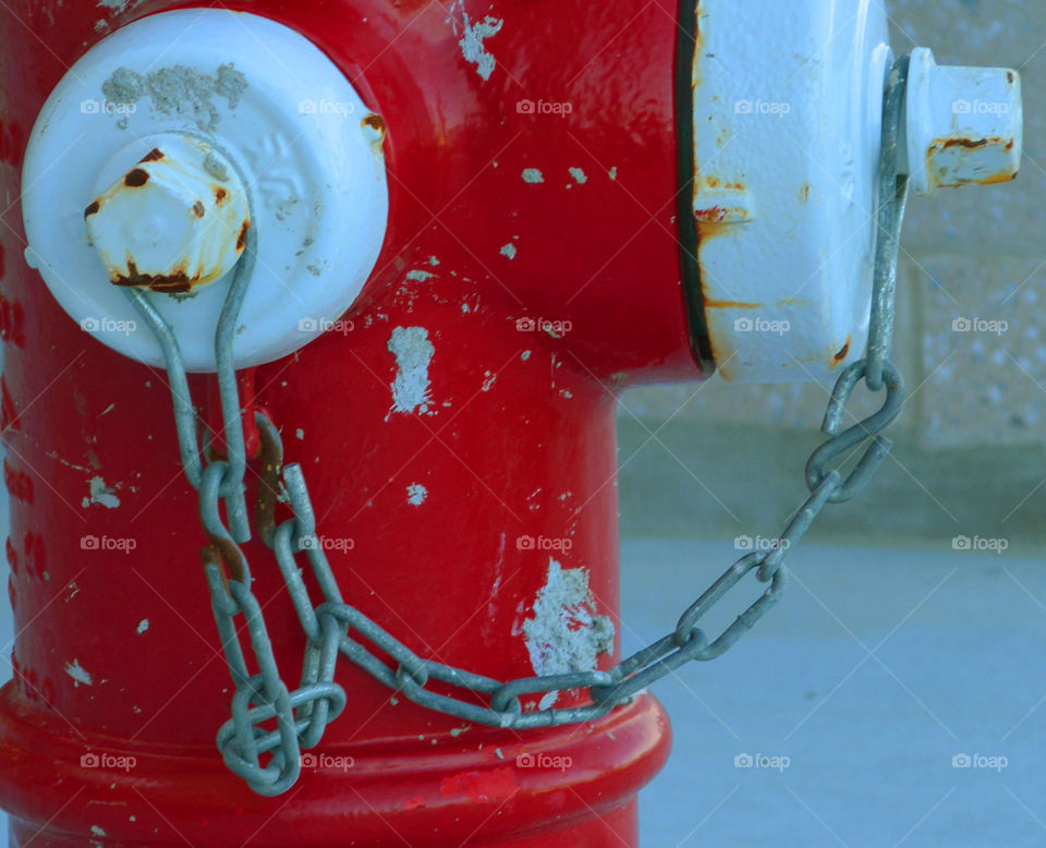 A pop of bright red is shown in this photo of a worn fire hydrant 