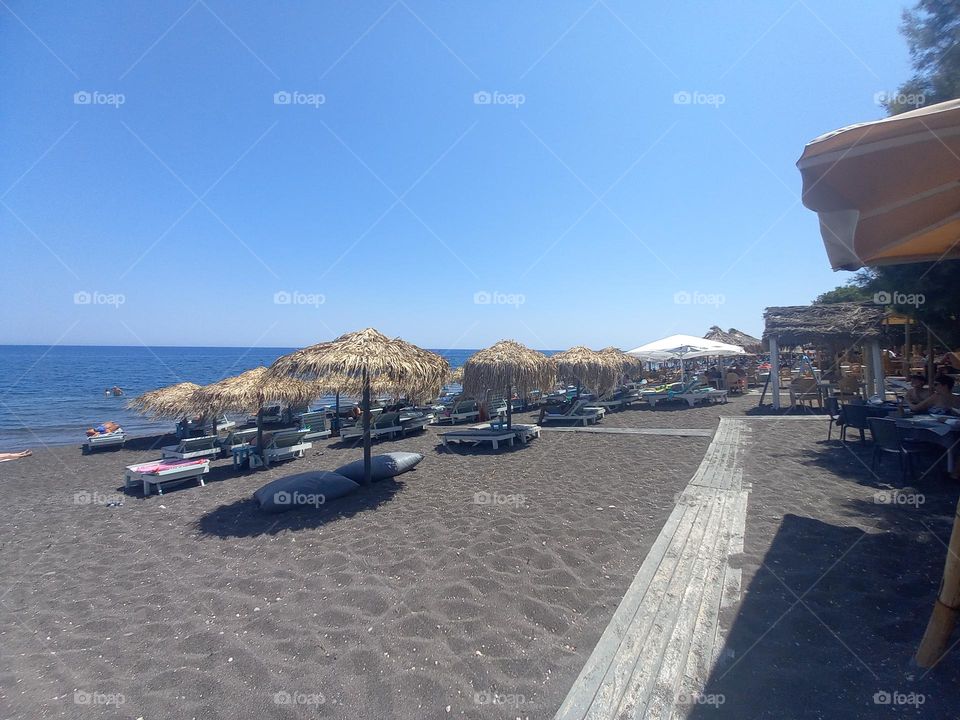 This is a part of a beautyful beach in Santorini. It's called Perissa and it is known for its characteristic black sand. Next to the beach there are many taverns, where you can taste the local cuisine.