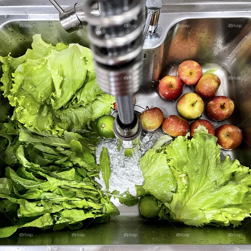 Vegetables and fruits in the sink with an open tap