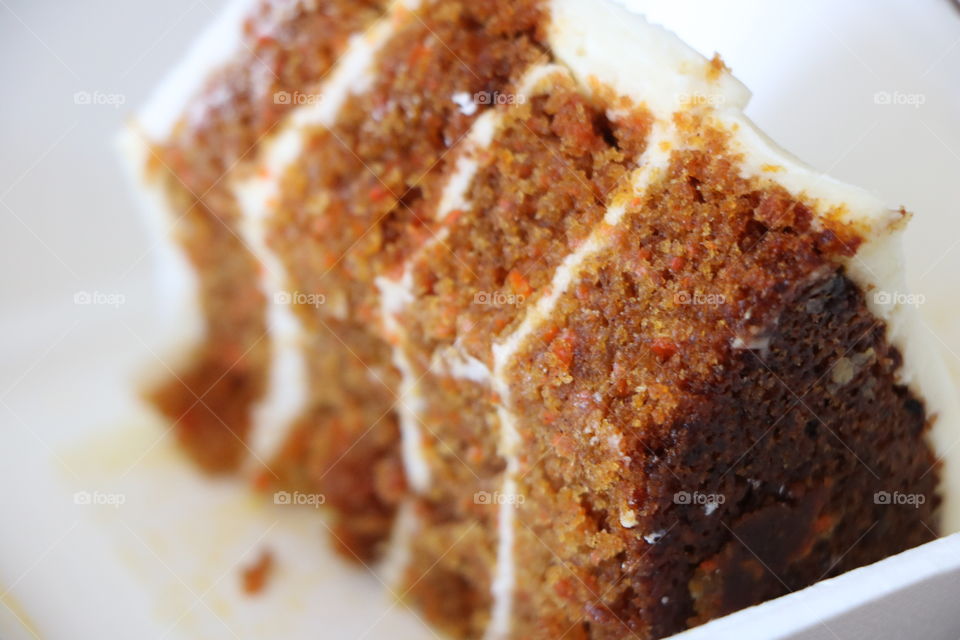 Carrot cake on a white plate with cream cheese filling