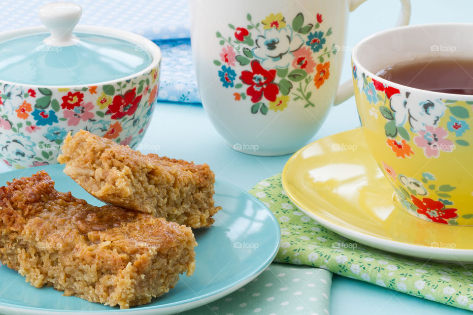 Afternoon tea with cake and flapjack in floral crockery.