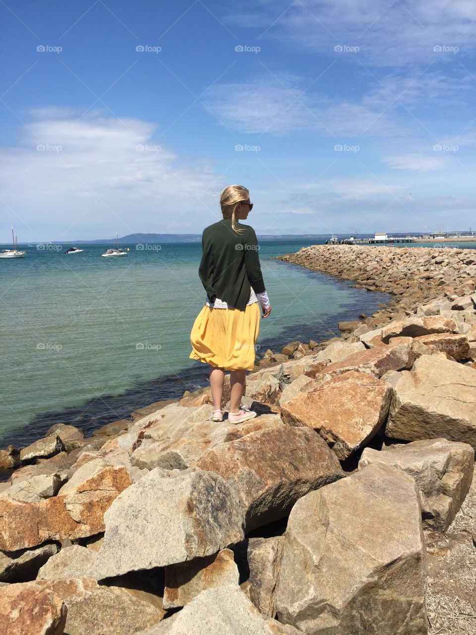 Girl looking at blue water coastline waves rocks