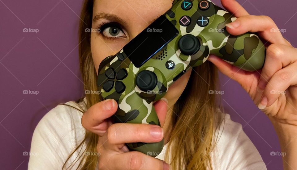 Girl gamer facing camera holding up her army camo game controller