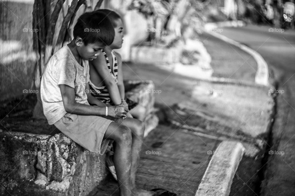 Black and white of two asian street kids hanging out on side of the street on a blurred S-curve background shot with helios 44M Lens.
