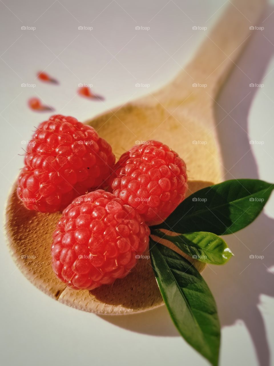 Three raspberries on a wooden spoon