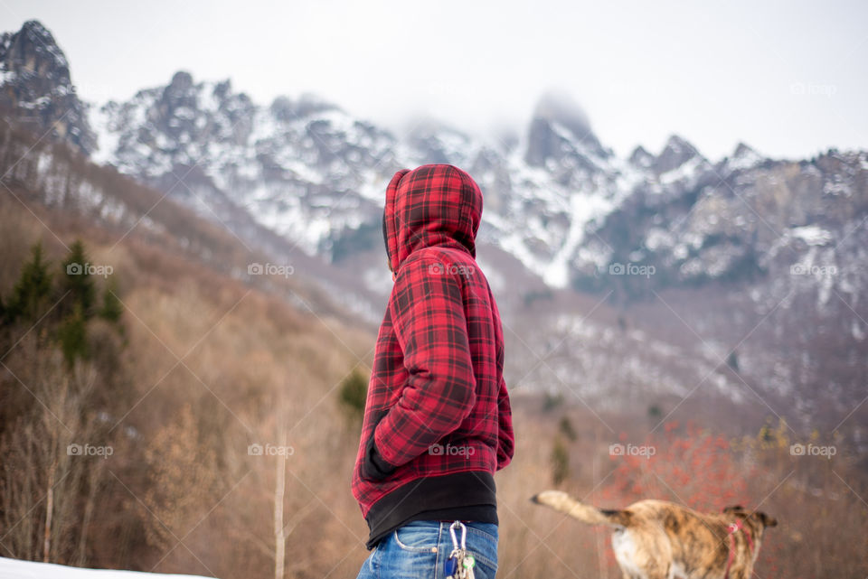 man with dog hike against snowcapped mountains