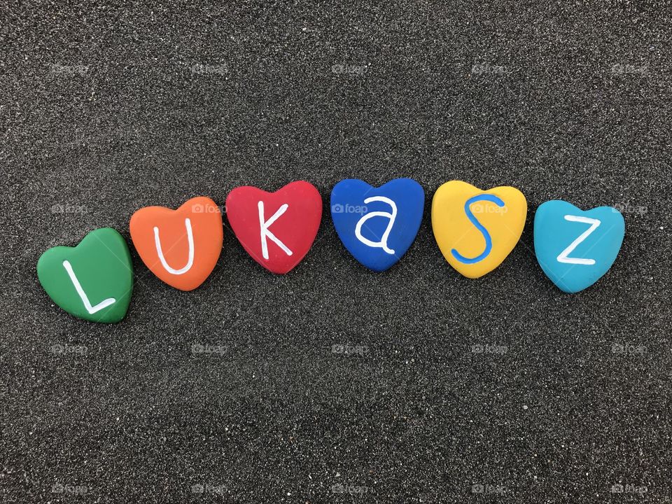 Lukasz, polish masculine day with colored heart stones over black volcanic sand