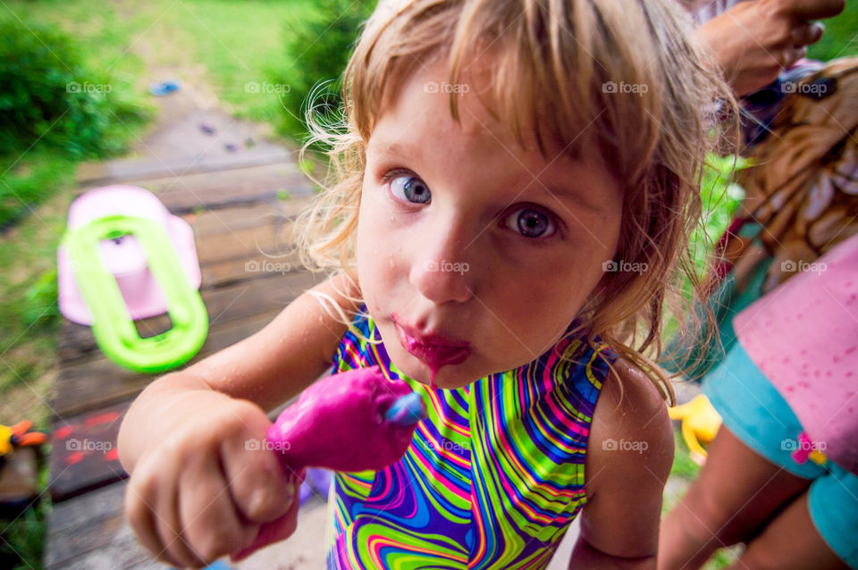 little girl is eating an ice cream messily