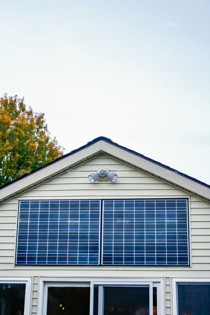 Alternative energy home solar panels in fall, portrait.