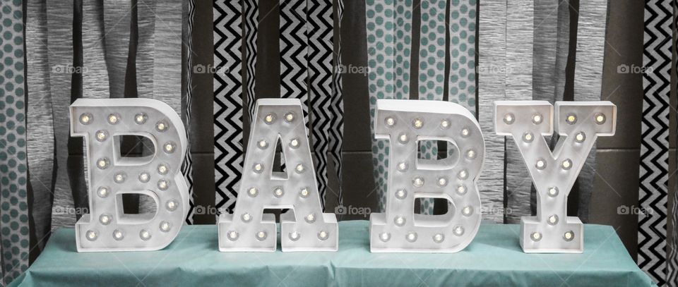 A sign from a baby shower for a boy. The decorations are patterned and designed. The blue is is added for the boy. 