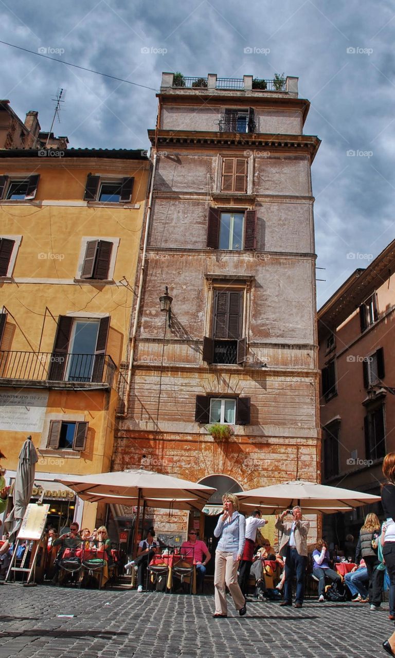 Fun and festivities. People have fun and have a festive atmosphere in a Roman plaza surrounded by colorful buildings