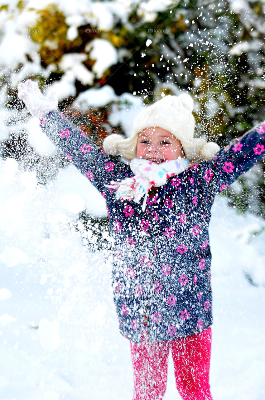 A YOUNG WHITE GIRL, AGED SIX, HAS FUN PLAYING IN THE SNOW.