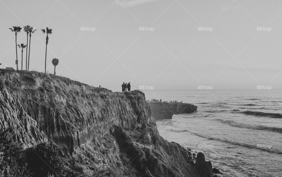 People stand on the cliffs of San Diego in black and white