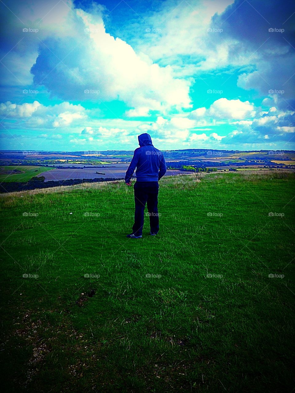 Rear facing man on a hill looking out into the distance 