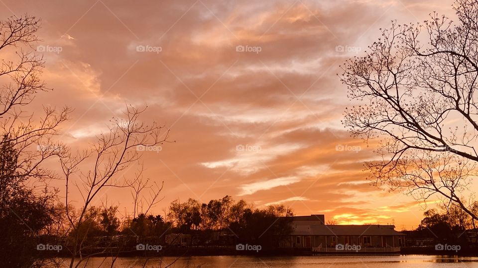 Deep Sunset Colors is upon the Beautiful Sunset also sky reflections silhouetted across colorful Lake waters. 