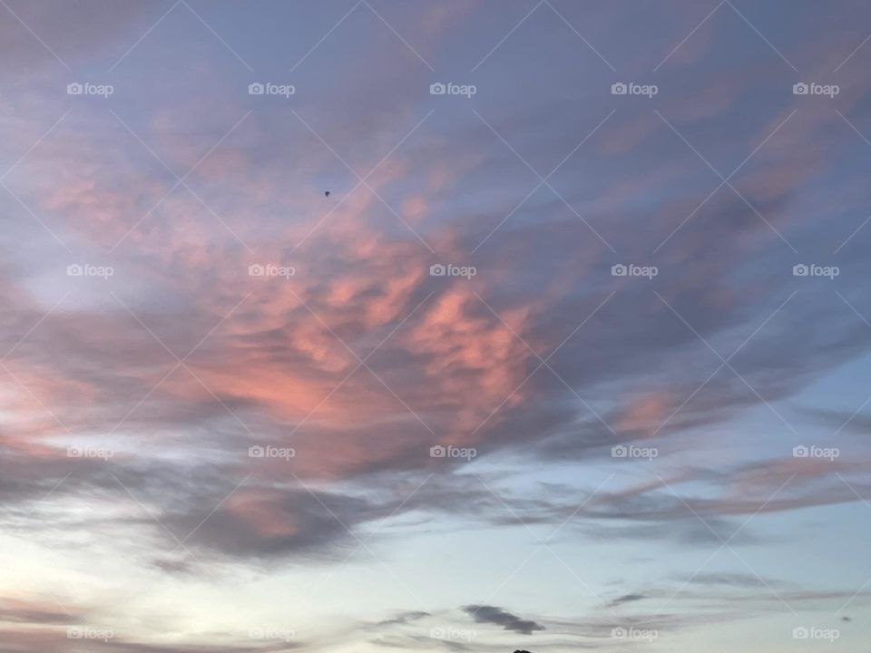Grey and pink clouds with the blue sky behind them.